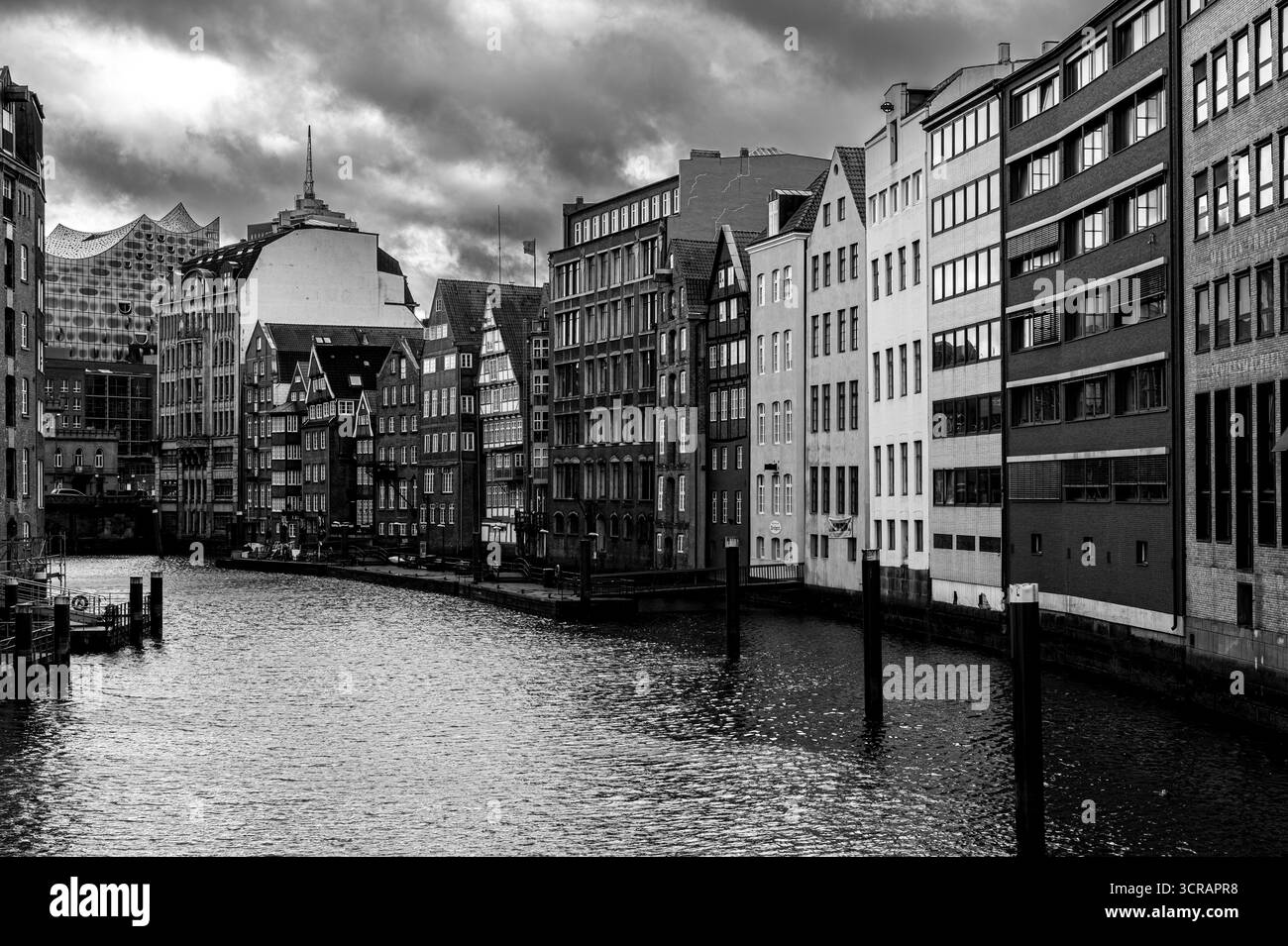 Dramatische schwarz-weiße Stadtlandschaft mit historischen Kanalbauten in Hamburg mit bewölktem Himmel, die klassische europäische Architektur zeigen. Perfekt für urb Stockfoto