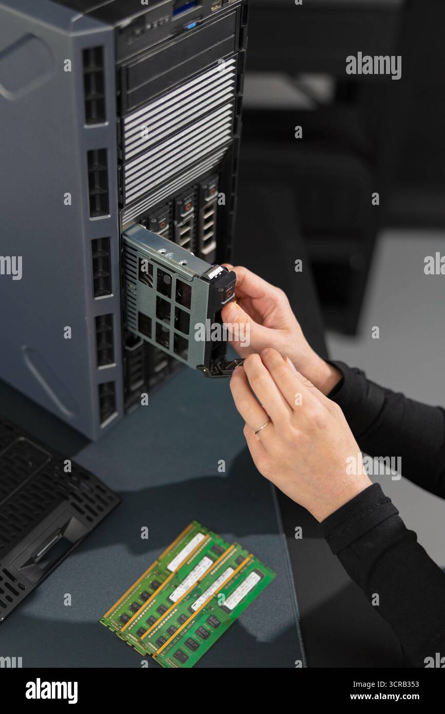 Weibliche IT-Techniker installieren die PCIe-Erweiterungskarte während der Wartung und Aktualisierung im Server-Rack Stockfoto
