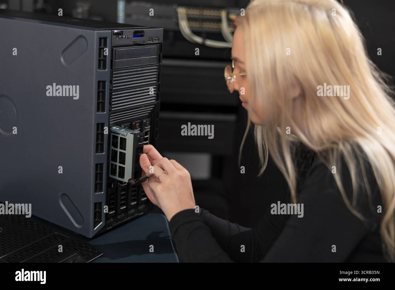 IT-Technikerin im Alter von 20 Jahren, die an einem Server-Rack in einem Rechenzentrum arbeitet Stockfoto