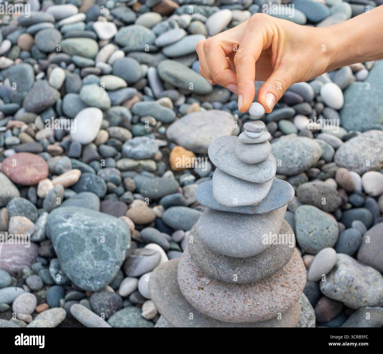 Eine Frau, die am Strand einen Steinhaufen macht Stockfoto