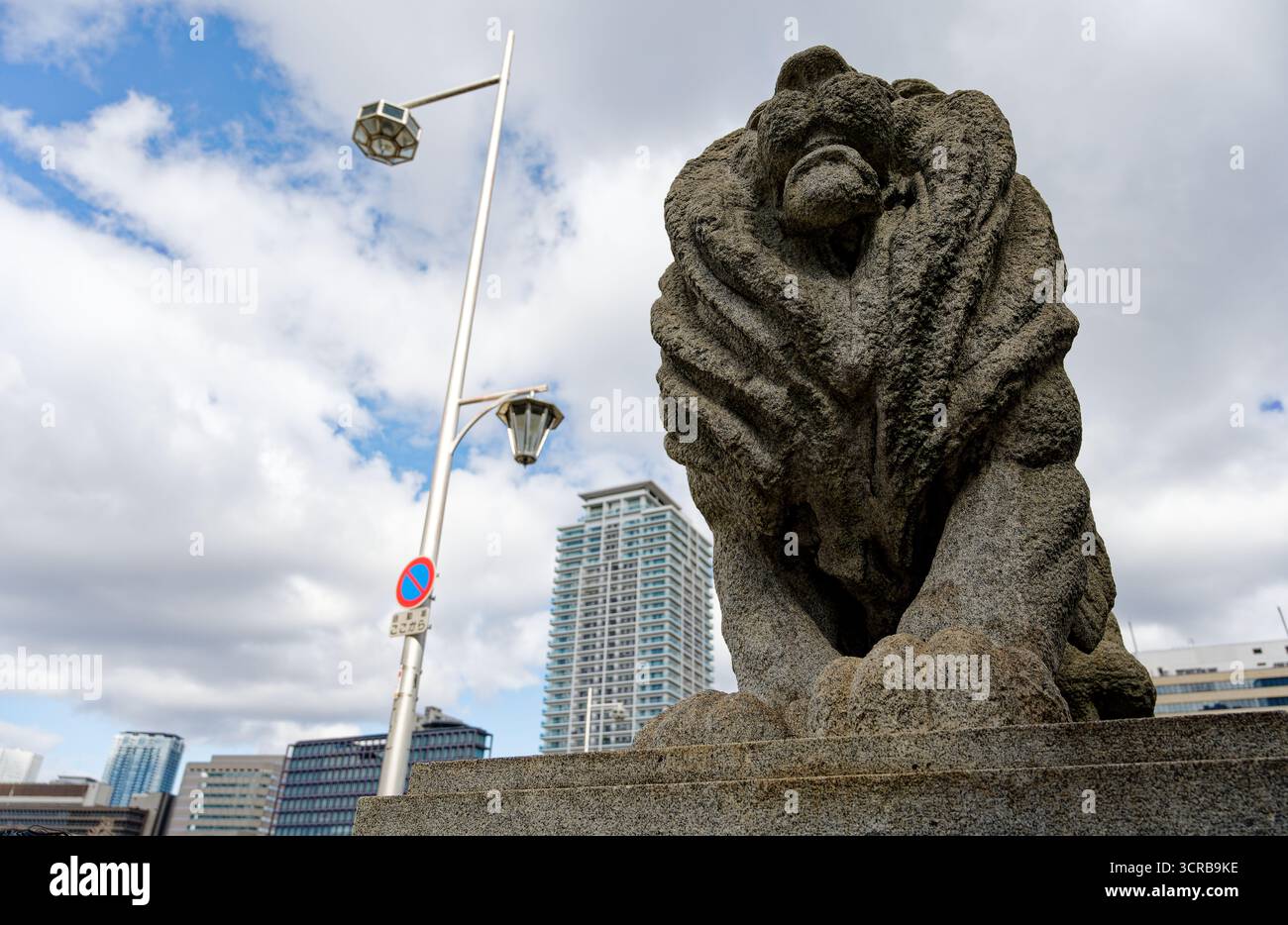 Steinlöwe bewacht die Naniwa-Brücke in Osaka unter einem teilweise bewölkten Himmel Stockfoto