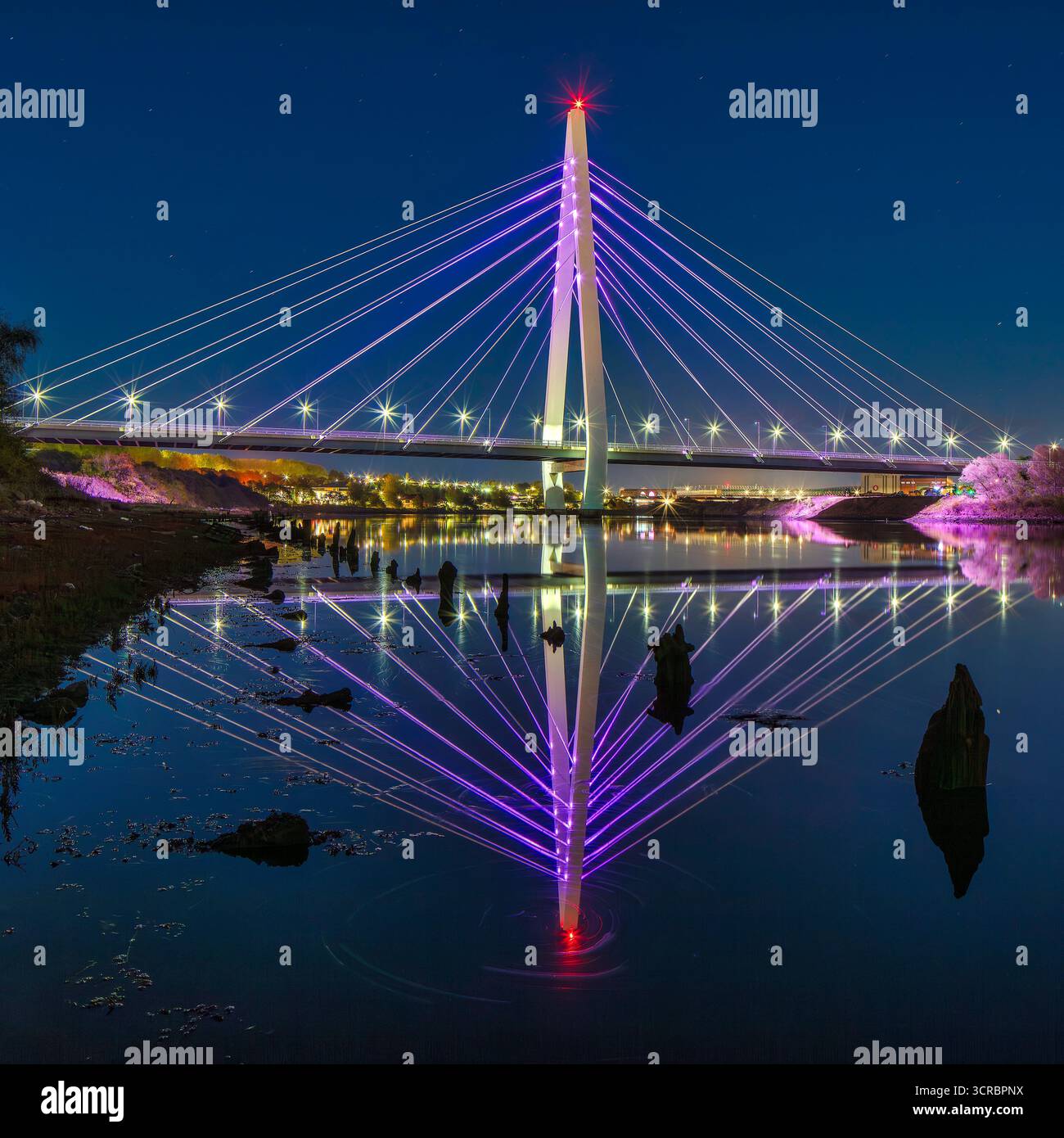 Ein Blick in die Dämmerung der beleuchteten Northern Spire Bridge in Sunderland, die sich im River Wear spiegelt und flussabwärts in Richtung Stadtzentrum blickt Stockfoto