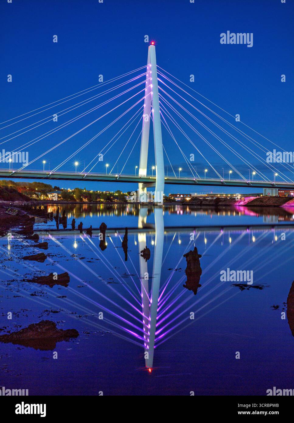 Ein Blick in die Dämmerung der beleuchteten Northern Spire Bridge in Sunderland, die sich im River Wear spiegelt und flussabwärts in Richtung Stadtzentrum blickt Stockfoto