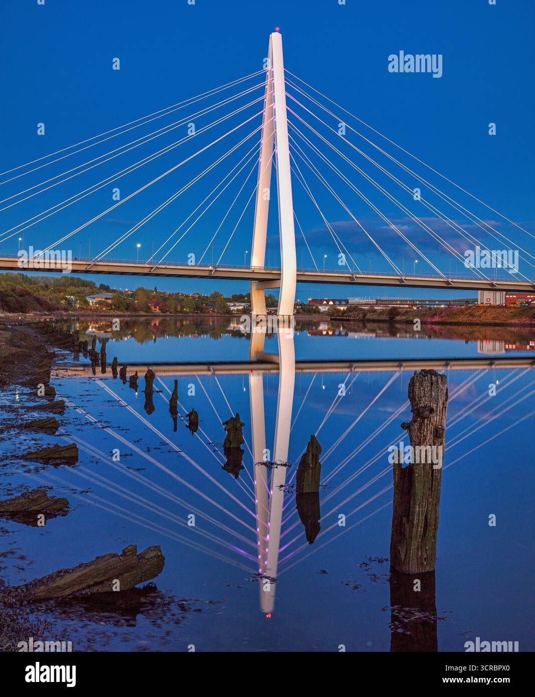 Ein Blick in die Dämmerung der beleuchteten Northern Spire Bridge in Sunderland, die sich im River Wear spiegelt und flussabwärts in Richtung Stadtzentrum blickt Stockfoto