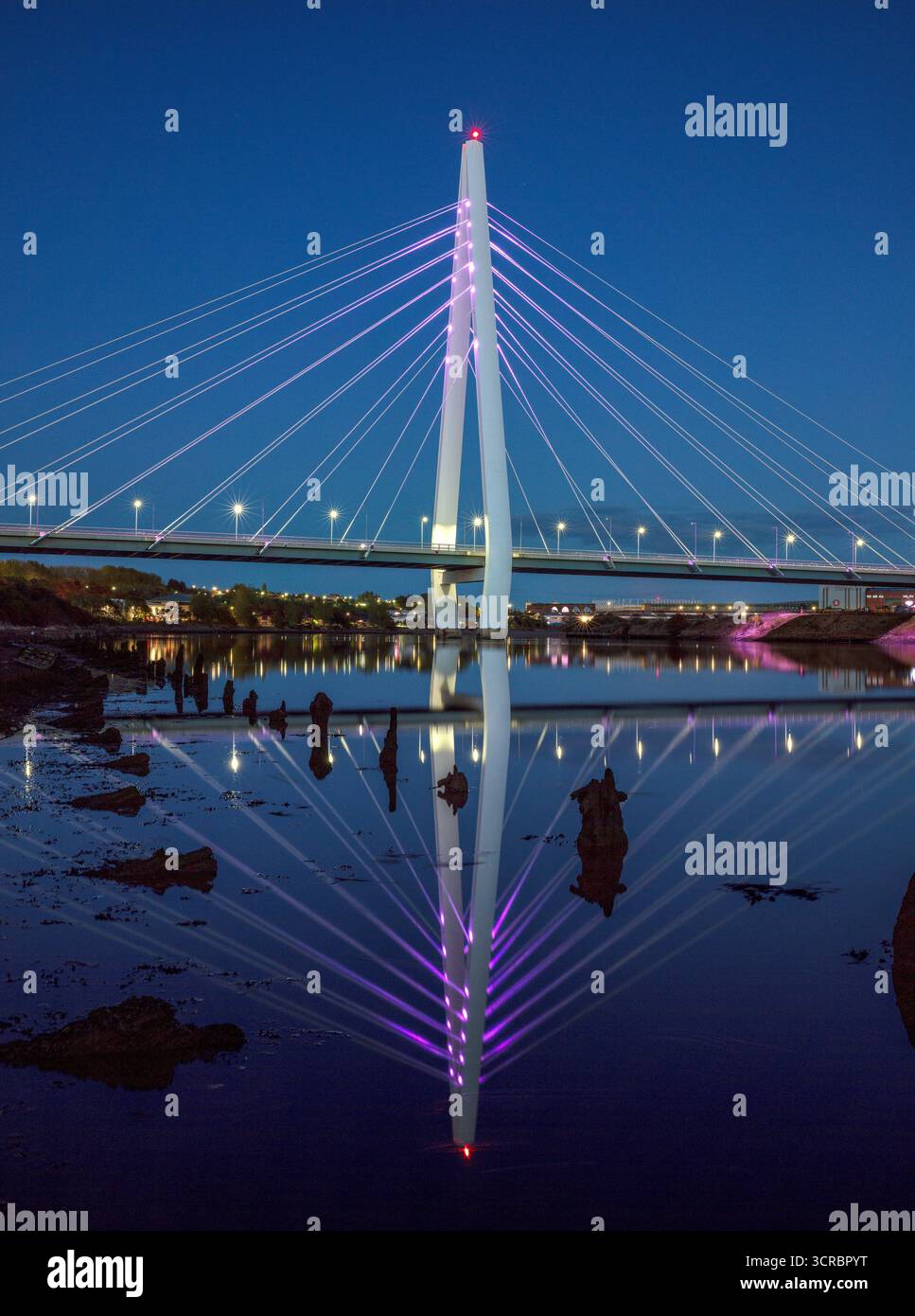 Ein Blick in die Dämmerung der beleuchteten Northern Spire Bridge in Sunderland, die sich im River Wear spiegelt und flussabwärts in Richtung Stadtzentrum blickt Stockfoto