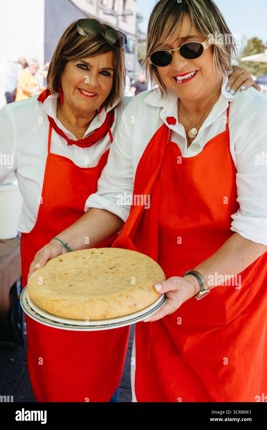 Lächelnde Frauen posieren mit einer großen Tortilla bei einer festlichen Veranstaltung im Freien Stockfoto