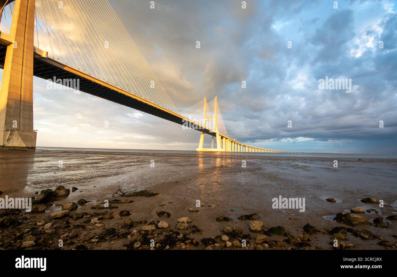 Vasco da Gama Brücke bei Sonnenuntergang mit dramatischen bewölkten Himmel in Lissabon Stockfoto