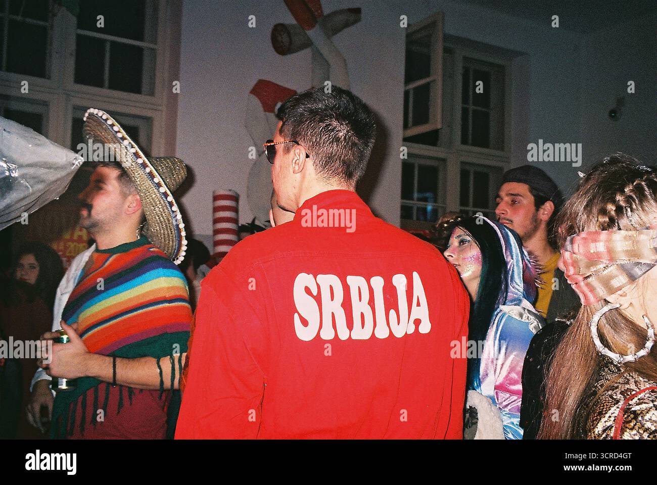 35mm Farbfilmfoto einer Studentenkostümparty an einer Universität in Belgrad. Blitzlicht, chaotisch, unterhaltsam, raue Energie – analoge Nightlife-Momentaufnahme. Stockfoto