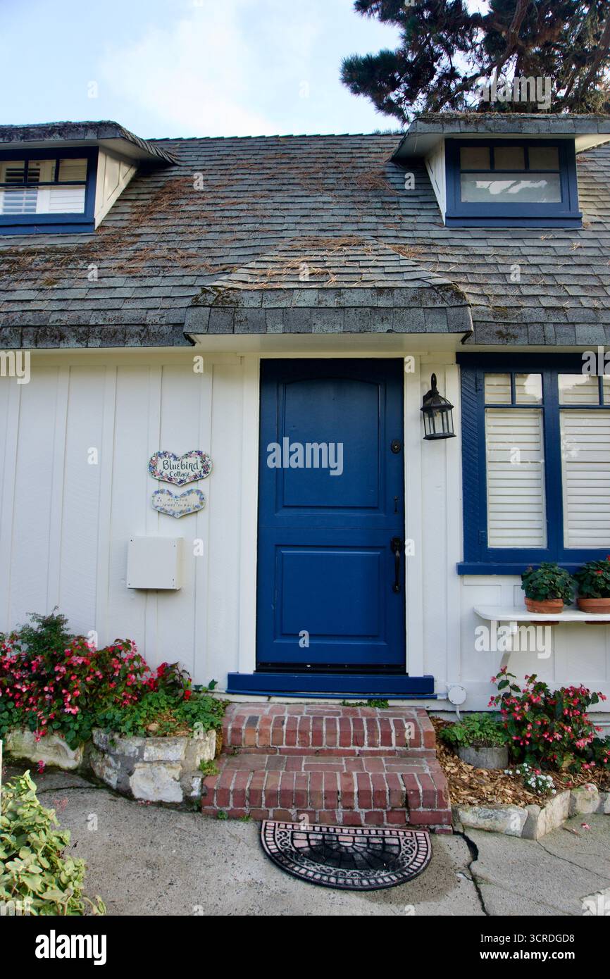 Redaktionelles Architekturbild des Bluebird Cottage in Carmel, Kalifornien, mit einer marineblauen Tür, Ziegeltreppen, Blumenkästen und Cottage-Stil de Stockfoto