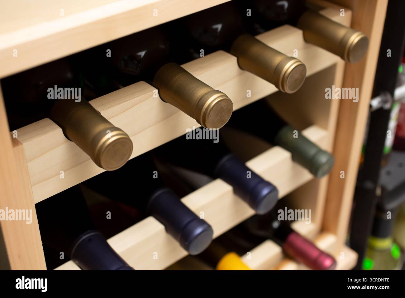 Blick auf mehrere Weinflaschen in einem hölzernen Weinregal. Stockfoto