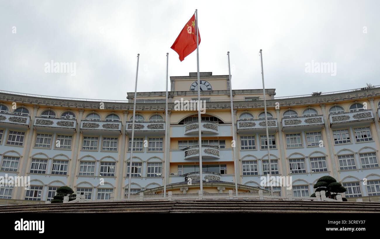 Die rote chinesische Flagge fliegt über einem historischen Gebäude und markiert den Nationalfeiertag mit Stolz und kultureller Einheit. Stockfoto