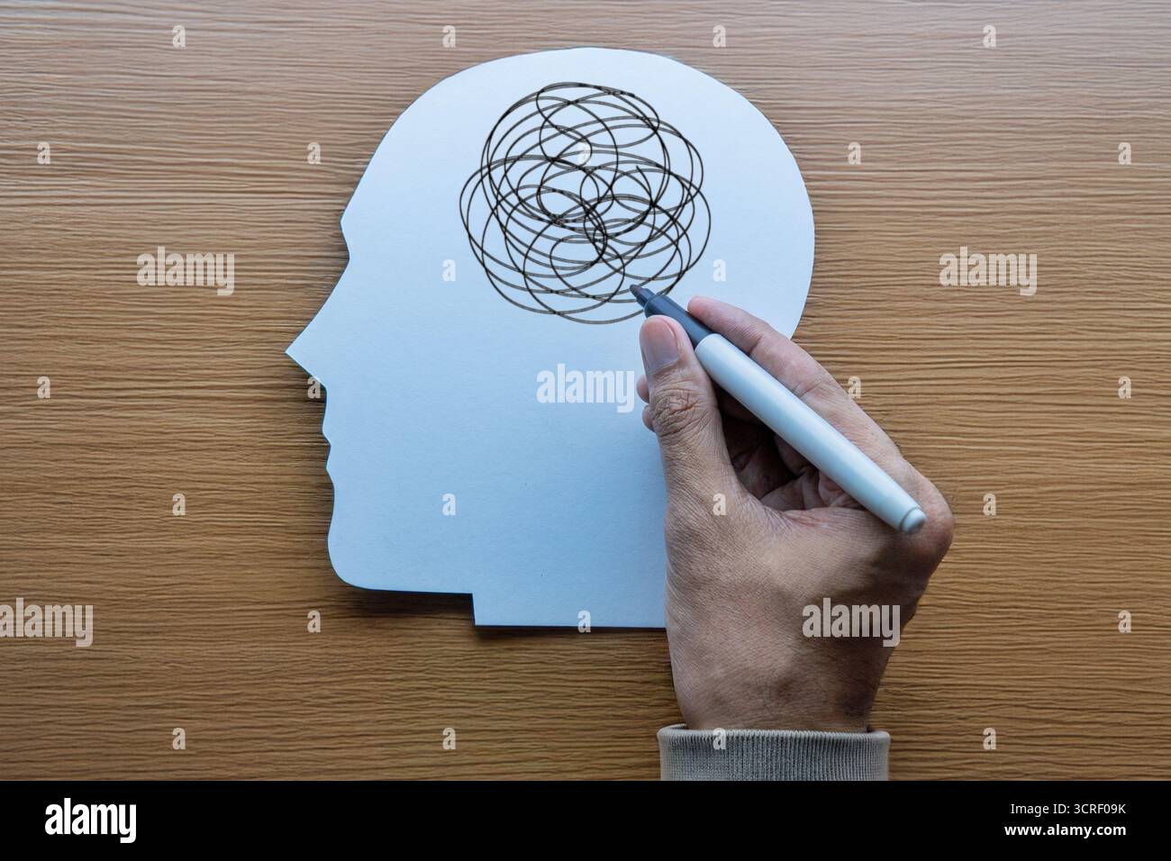 Menschlicher Kopfausschnitt mit einer Hand, die chaotische Kritzeleien zeichnet. Stress, Angst, Verwirrung, psychische Störungen, Depressionen und psychische Probleme. Stockfoto