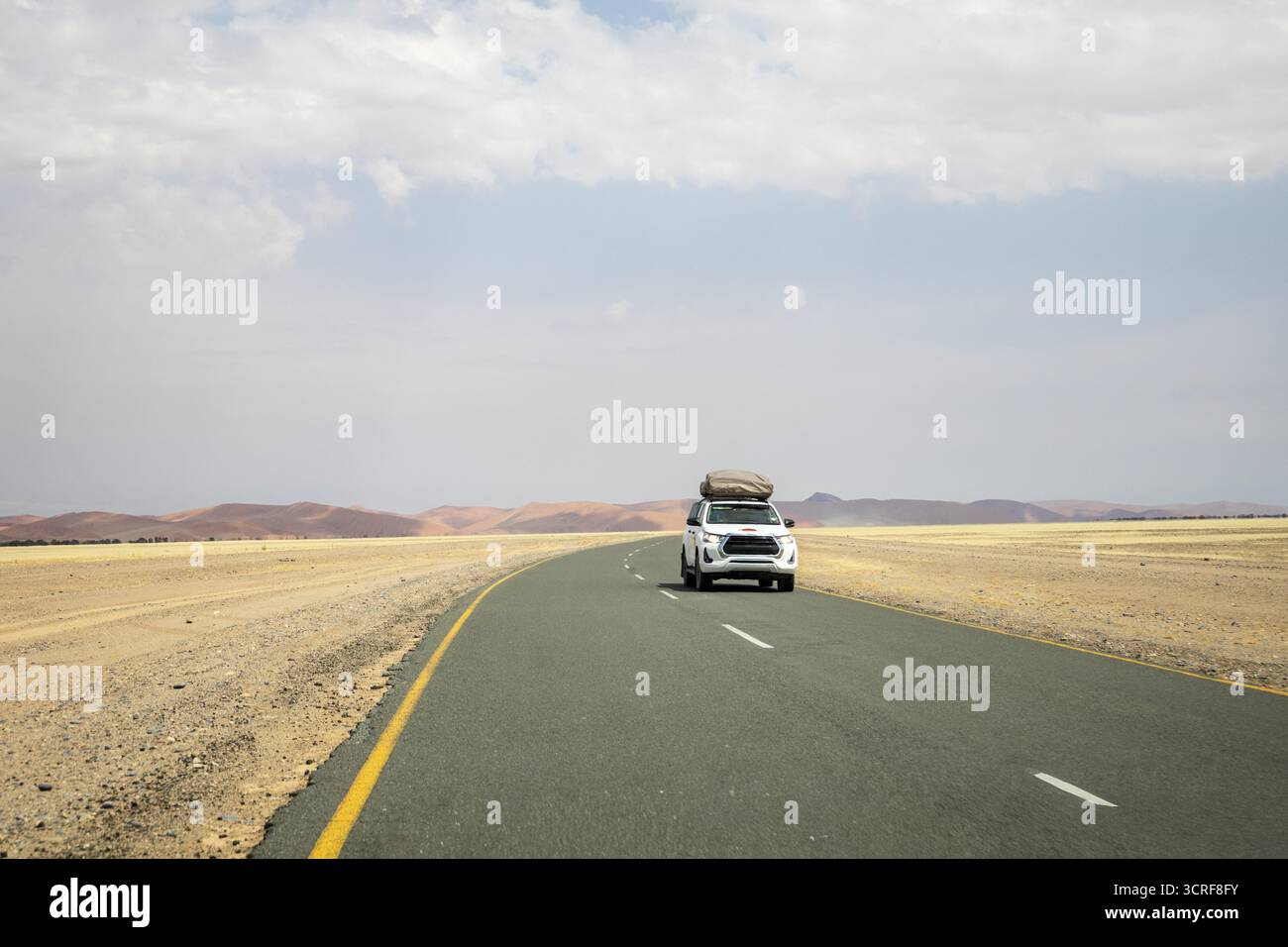 Im Inneren von Sossusvlei ziehen sich Schotterstraßen und ein Auto durch rote Dünen nach Deadvlei, Big Daddy und Sesriem Canyon, wo Sie malerische, staubige Wüstenausblicke genießen können. Nami Stockfoto