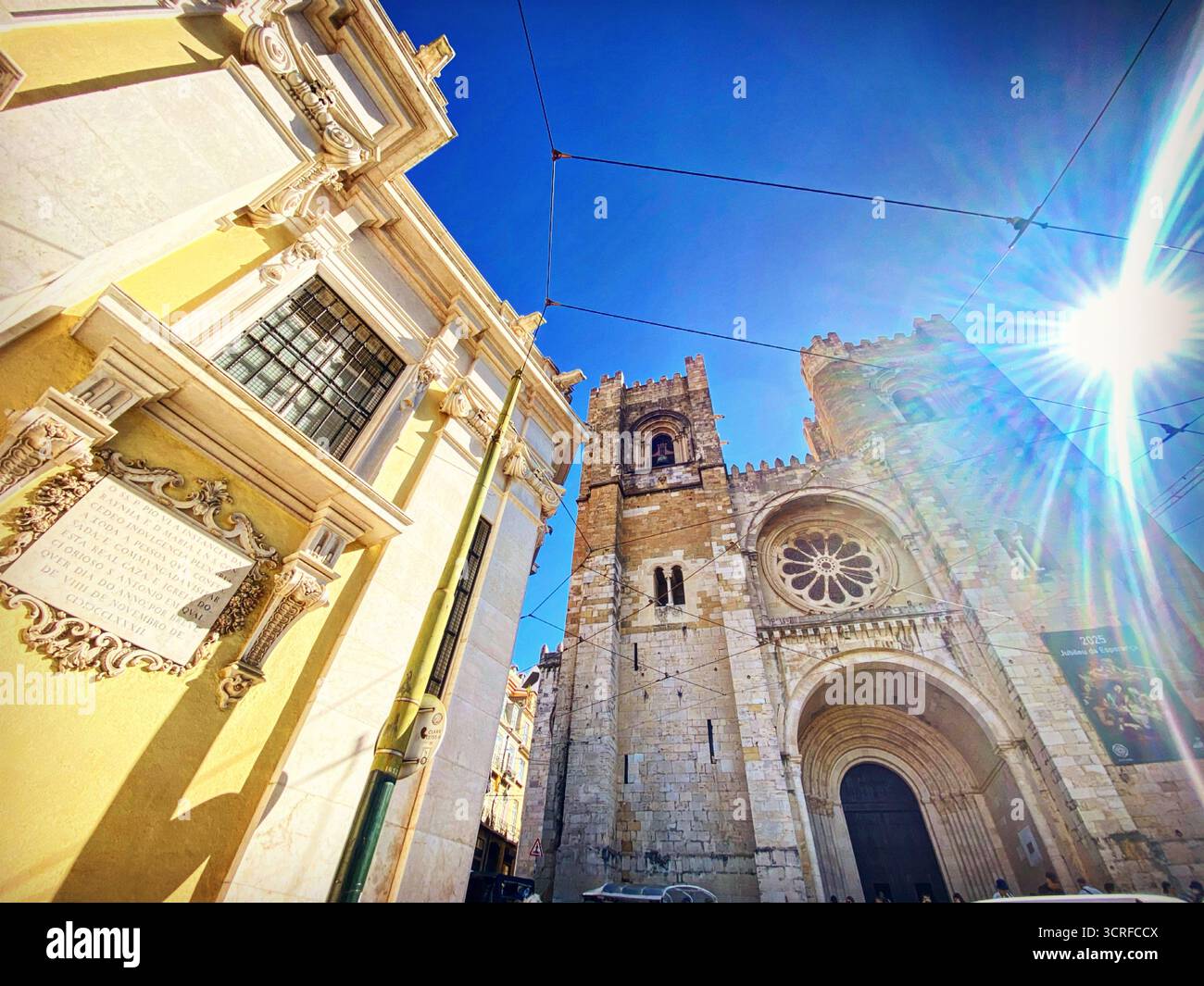 Die Sünde erstrahlt durch das Geburtshaus des Heiligen Antonius von Lissabon (links) und die Kathedrale von Lissabon in Lissabon, Portugal - Smartphone-aufgenommenes Stockfoto