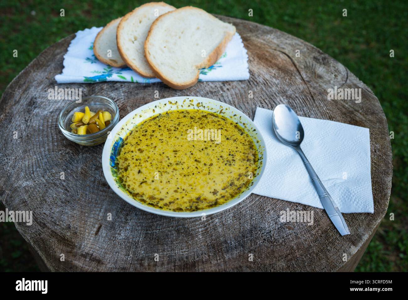 Schweinepilzsuppe, serviert im Freien mit Brotscheiben und eingelegter Chili auf einem rustikalen Baumstumpftisch im Apuseni-Gebirge, Rumänien Stockfoto