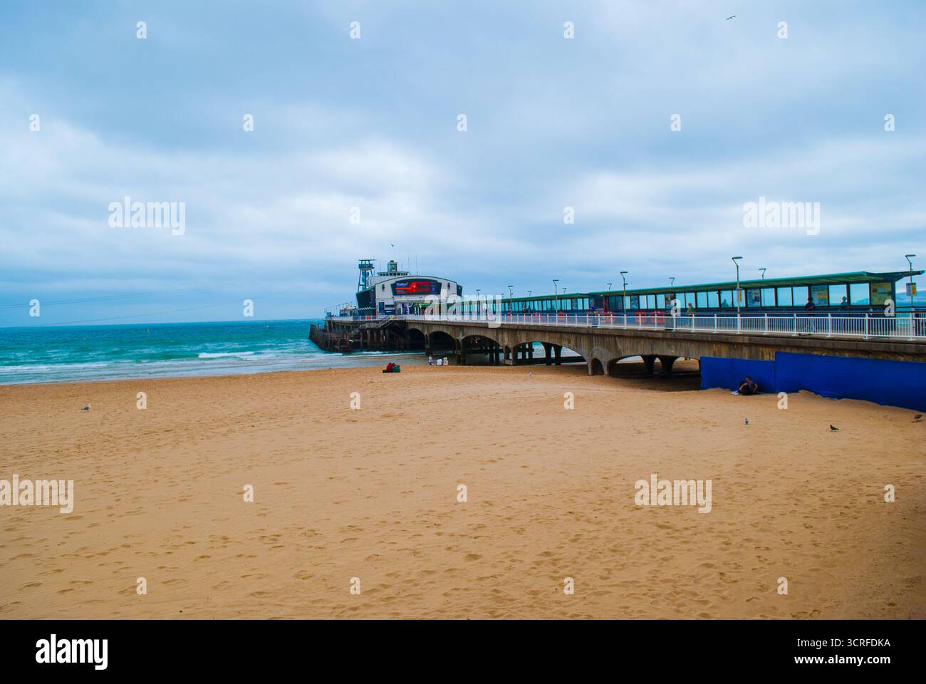 Blick auf den Bournemouth Pier, der sich bis ins Meer erstreckt, mit seiner lebhaften Struktur im Kontrast zum Sandstrand Bournemouth, Bournemouth, Großbritannien. Stockfoto