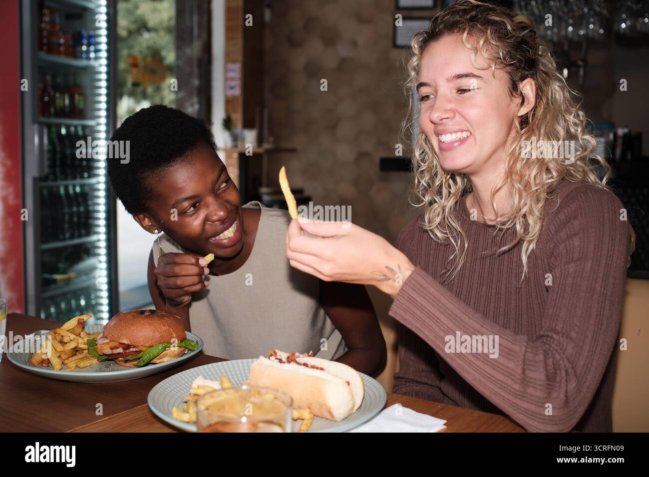Verschiedene Freunde, die Fast Food genießen und Pommes frites teilen Stockfoto
