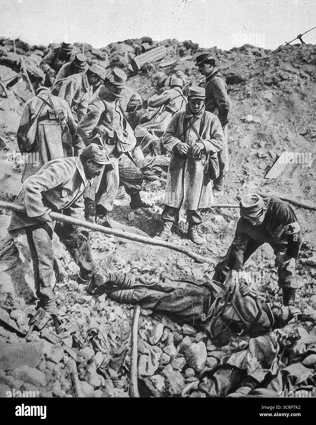 Französische Soldaten räumen einen neu gebildeten Muschelkrater nach einer Minenexplosion in Champagne während des Ersten Weltkriegs, März 1916. Gefallene deutsche Truppen, die bei einem gescheiterten Gegenangriff getötet wurden, werden auf dem Schlachtfeld begraben, während Kameraden die Position unter fortgesetztem Beschuss organisieren. Dieses Bild, das in Le Miroir veröffentlicht wurde, veranschaulicht die düsteren Realitäten des Grabenkriegs und den massiven Einsatz von Sprengstoff, der die Landschaft der Westfront im Ersten Weltkrieg neu gestaltet hat. Stockfoto