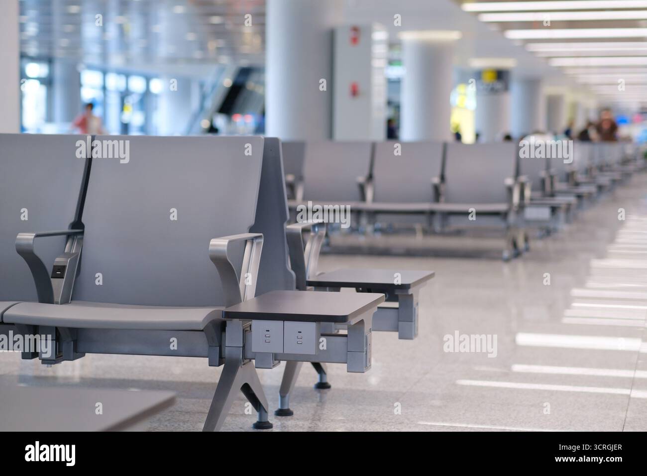 Die Sitzplätze in einem modernen Flughafenterminal bieten während der Mittagszeit einen sauberen, organisierten Raum, der den Reisenden eine angenehme Atmosphäre bietet Stockfoto