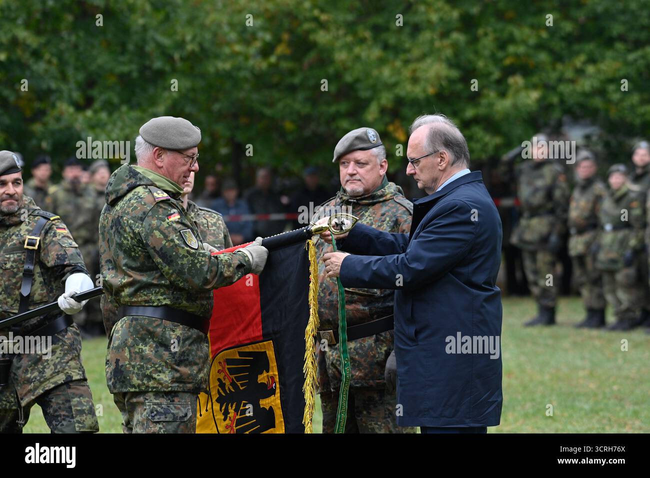 1. Oktober 2025, Sachsen-Anhalt, Möckern: Reiner Haseloff (r, CDU), Ministerpräsident von Sachsen-Anhalt, befestigt das Band mit dem Namen des Regiments an den Fahnenmast bei der Übergabe der Truppenfahne an das Innenwacherregiment 6. Die Soldaten des Regiments hatten sich im Schlosspark Möckern für die Formationsrolle aufgestellt. Das Heimatschutz-Regiment 6 vereint zwei Unternehmen aus Berlin, zwei Unternehmen aus Potsdam und je eine Firma aus Magdeburg und Klietz und ist mit seinem Personal- und Versorgungsunternehmen, dem Spezialbetrieb und dem Ausbildungsbetrieb in Altengrabow stationiert. Foto: Klaus-Dietmar Gabbert/ Stockfoto