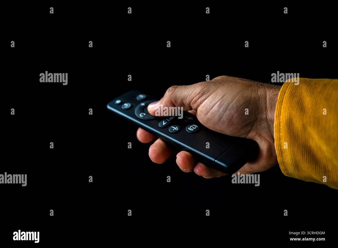 Steuerung mit Fernbedienung in der Hand vor dunklem Hintergrund Stockfoto