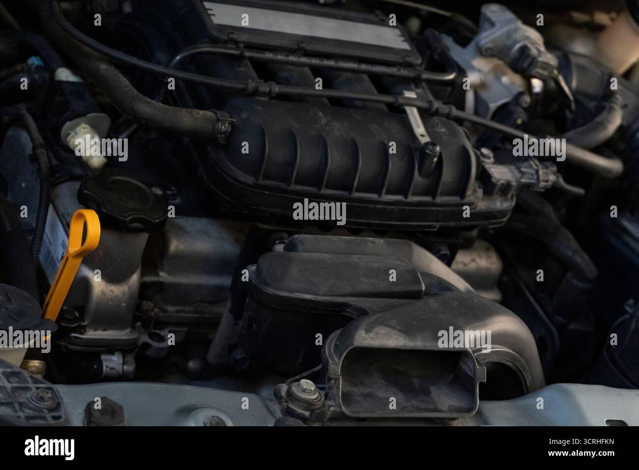 Detaillierte Nahaufnahme eines Fahrzeugmotors mit Luftansaugung, Schläuchen und Messstab für Fahrzeugwartung und -Technik Stockfoto