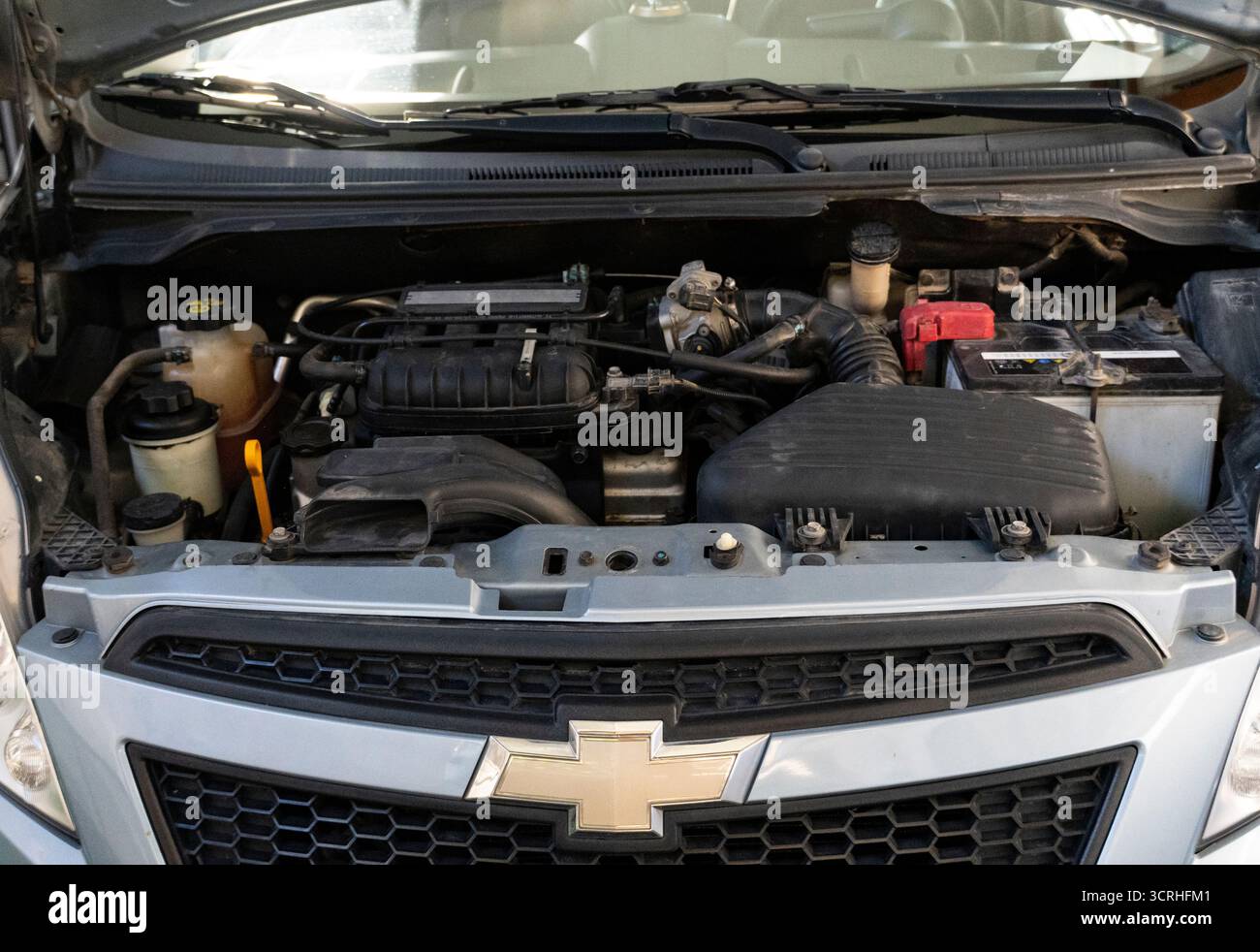 Hochwinkelaufnahme eines offenen Motorraums mit Motor, Batterie, Verkabelung und Flüssigkeitsbehältern, ideal für die Wartung und Reparatur von Fahrzeugen Stockfoto