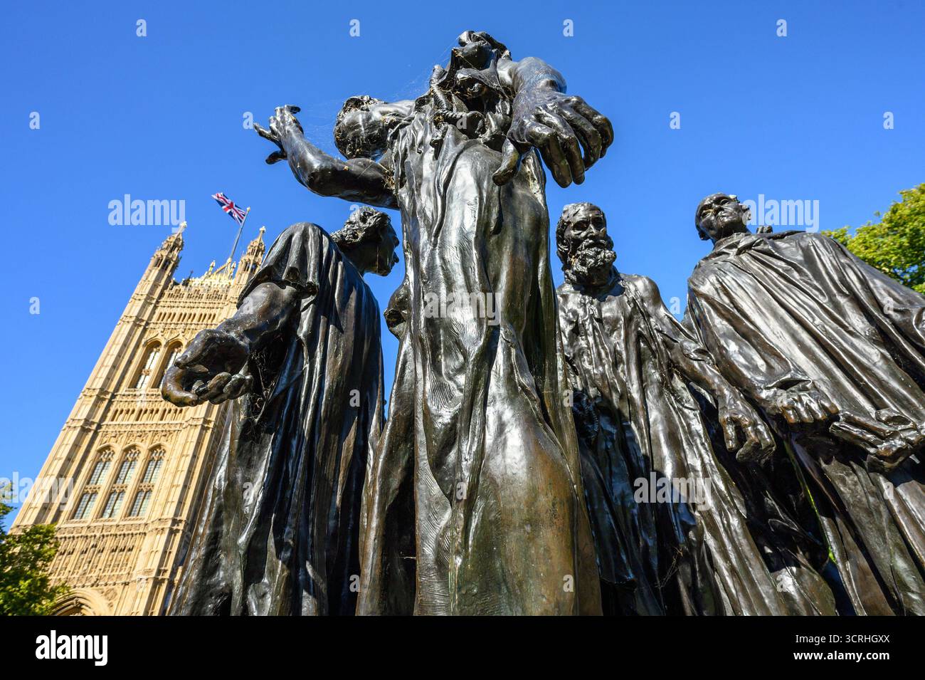 London, England, Großbritannien. Rodin's Burghers of Calais (1895) in den Victoria Tower Gardens, Westminster. Die Häuser des Parlaments dahinter. Die Bronze bildet einen nach Stockfoto