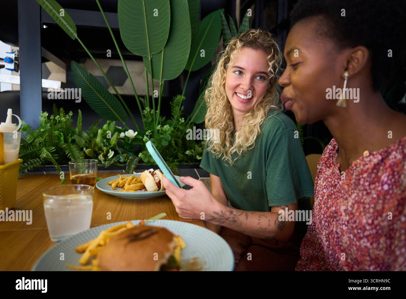 Verschiedene Freundinnen unterhalten sich lächelnd und genießen das Essen Restaurant Stockfoto