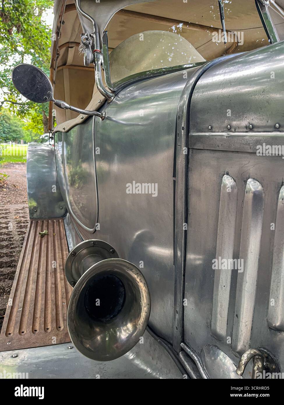 Ein Schlüssel mit Schlüsselanhängern wird in das Schlüsselloch einer Glastür mit Blick auf einen englischen Garten gesteckt - Smartphone-aufgenommenes Stockfoto