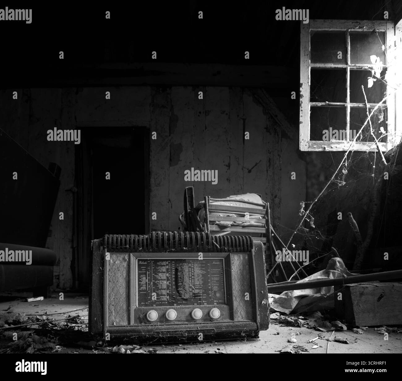 Vintage Radio im verlassenen Raum mit kaputtem Fenster und Spinnweben – atmosphärische Lost Place Photography in Soft Light Stockfoto