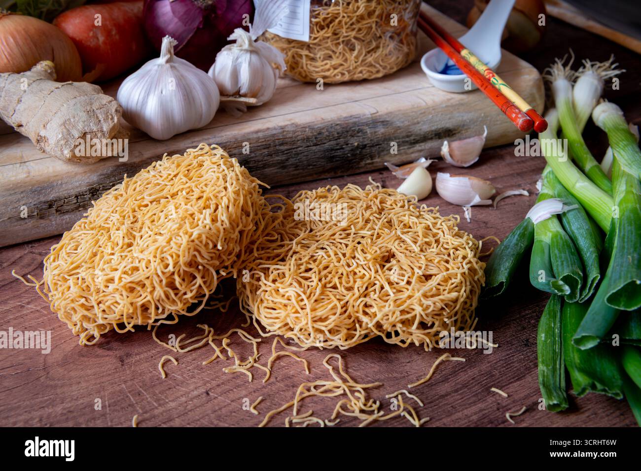 Getrocknete chinesische feine Weizennudeln auf einer Küchenarbeitsfläche zusammen mit verschiedenen Gemüsesorten. Stockfoto