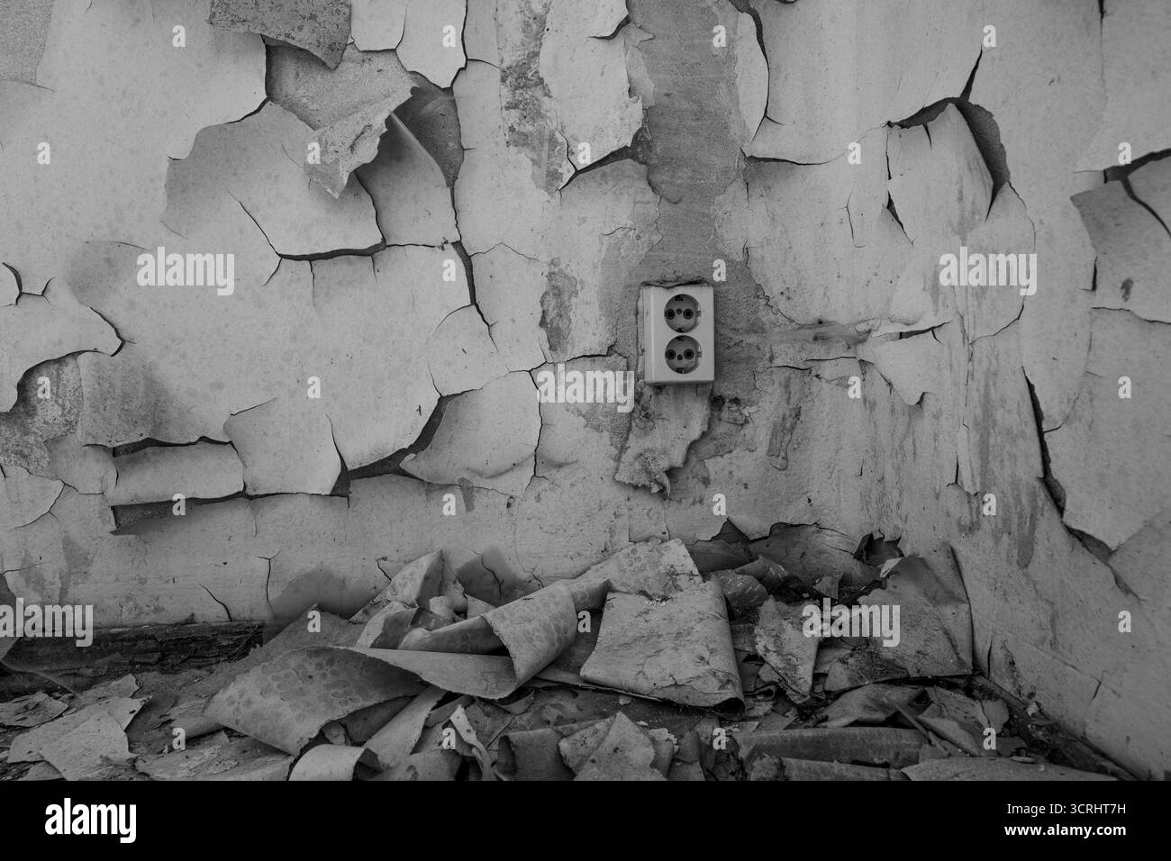 Verfallene Wand mit abblätternder Farbe und alter Steckdose im verlassenen Gebäude – strukturiertes Detail des urbanen Verfalls in neutralen Tönen Stockfoto