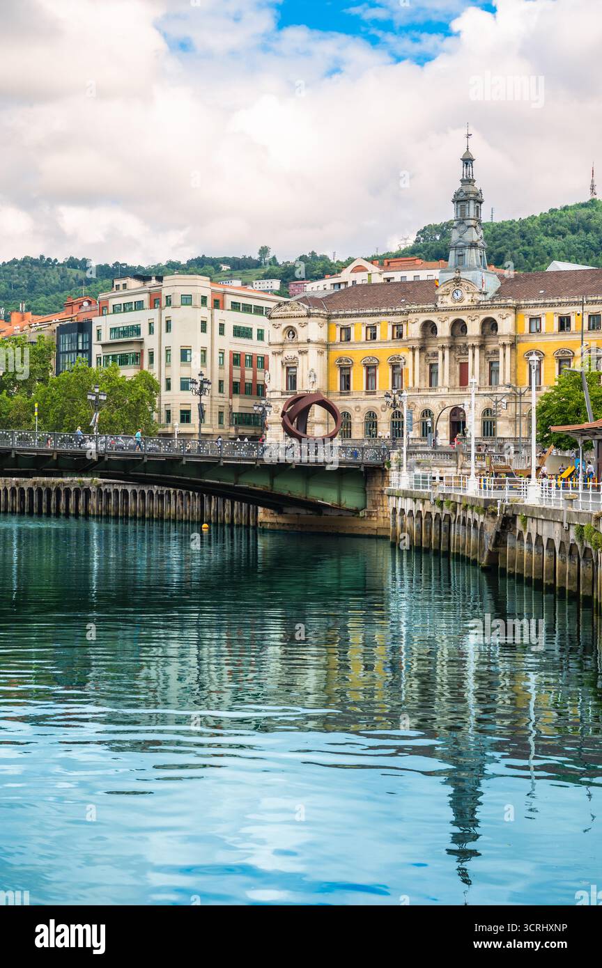 Farbenfrohes vertikales Reisefoto von Bilbao mit Brücke, Rathaus und Flussreflexion Stockfoto