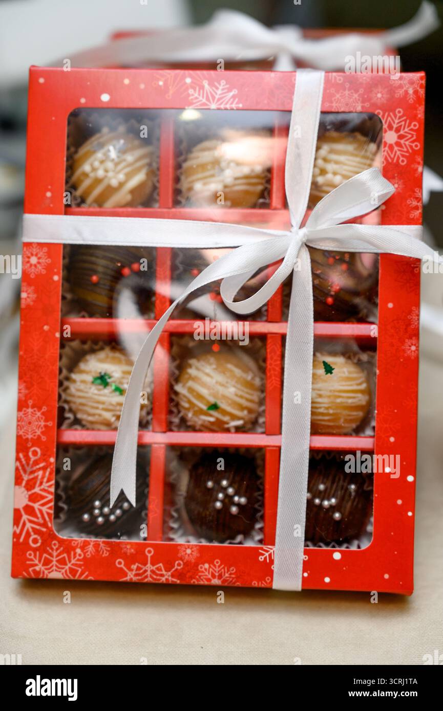 Eine Auswahl handgemachter Pralinen in Geschenkboxen. Eine Nahaufnahme einer Geschenkbox mit Schokoladenüberzug und bunten Streuseln Stockfoto
