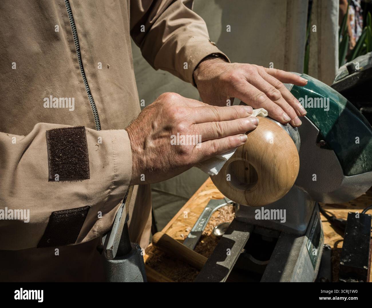 Ein Handwerker poliert eine Holzschale auf einer Drehmaschine Stockfoto