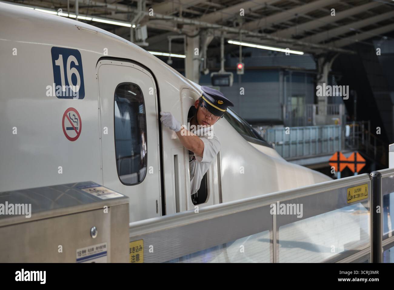 Japanischer Zugbegleiter in Uniform am Bahnsteig. Professionelles Eisenbahnpersonal, das einen effizienten Service auf Japans pünktlichen Transport bietet Stockfoto