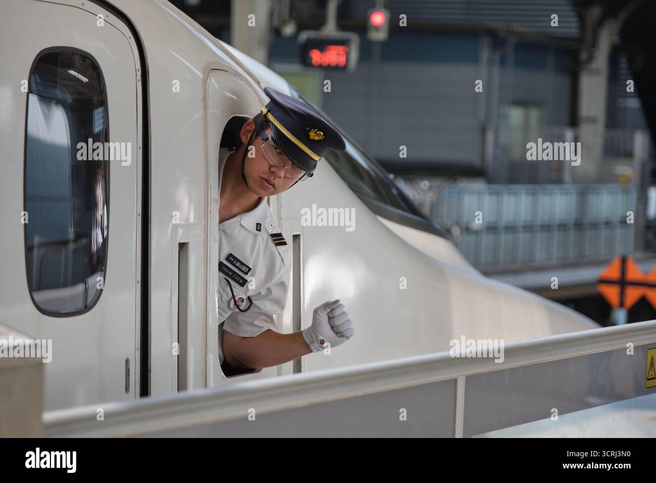 Japanischer Zugbegleiter in Uniform am Bahnsteig. Professionelles Eisenbahnpersonal, das einen effizienten Service auf Japans pünktlichen Transport bietet Stockfoto