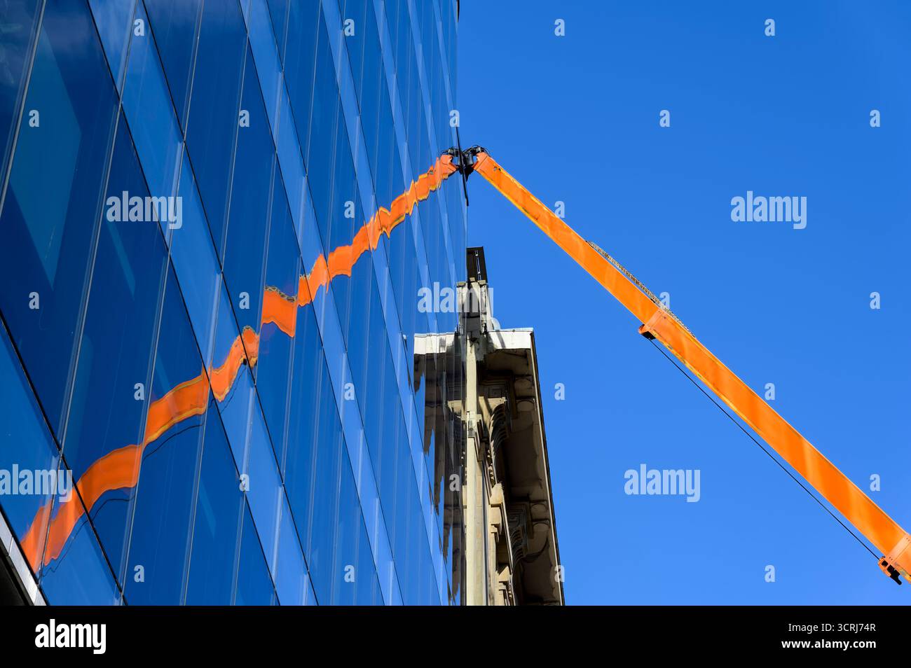 Reflexion eines hydraulischen Aufzugs in der Glasfassade eines Bürogebäudes, Großbritannien Stockfoto