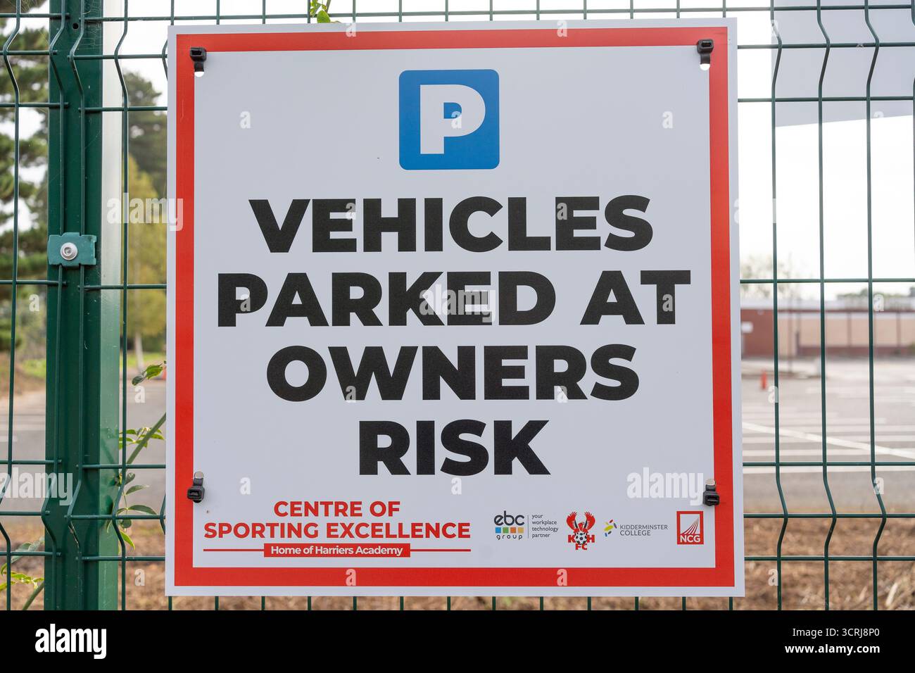 Fahrzeuge, die auf Risiko des Besitzers an einem Drahtzaun geparkt sind, UK. Stockfoto