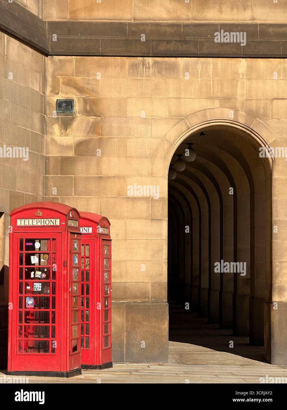 Rote traditionelle Telefonkioske vor den Durchgangsbögen im Rathaus von Manchester am Petersplatz Stockfoto