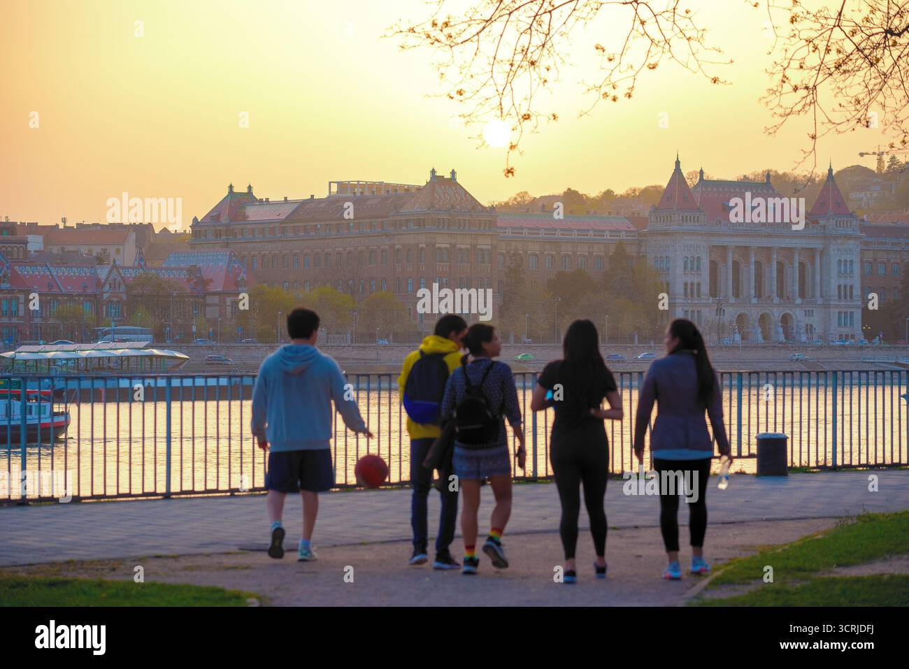 Gruppe junger Leute mit Ball am Fluss in der Stadt bei Sonnenuntergang Stockfoto