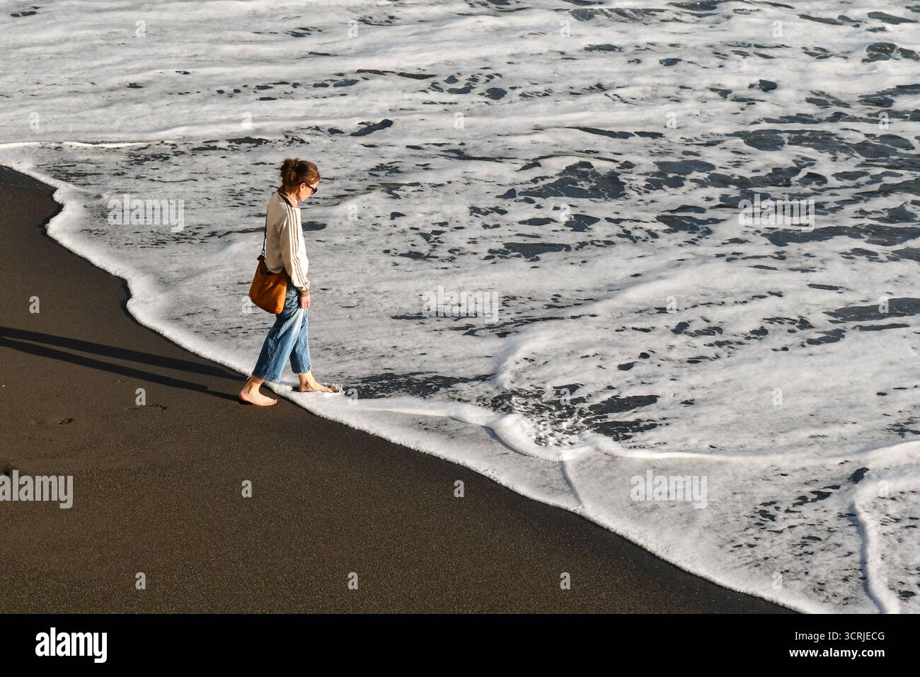 Hochwinkelansicht einer voll ausgezogenen und barfuß Frau am Ufer eines Strandes im Frühling, Genua, Ligurien, Italien Stockfoto