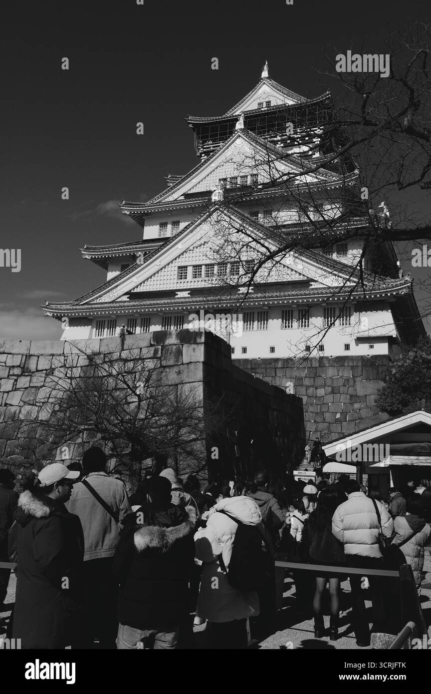 Besucher treffen sich am Fuße des Osaka Castle an einem klaren Wintertag in Schwarzweiß Stockfoto