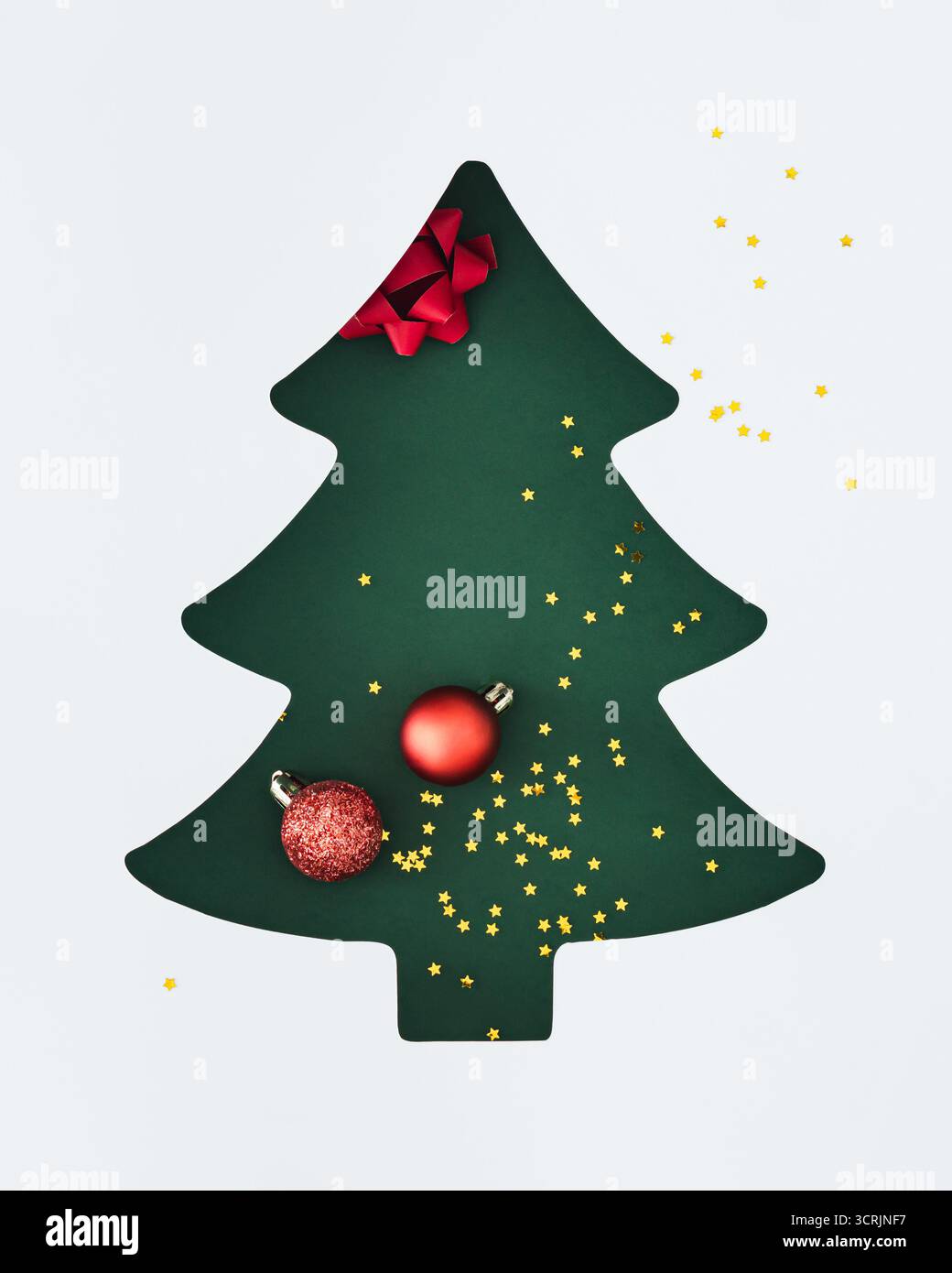 Kreativer Weihnachtsbaumausschnitt mit roten Kugeln und goldenen Sternen auf grünem Hintergrund. Perfekt für Urlaubsthemen. Minimales Weihnachtskonzept. Stockfoto
