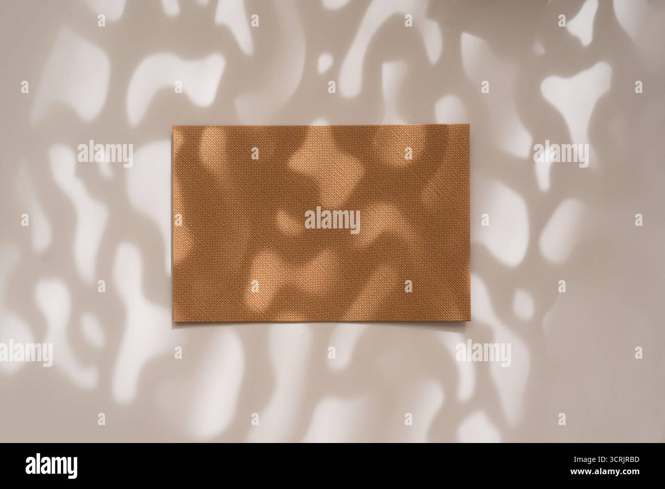 Braun-oranges leeres Kraftblatt mit künstlerischen Schatten auf weißem Hintergrund, flache Lay. Einladungs- oder Grußkartenmotiv Stockfoto