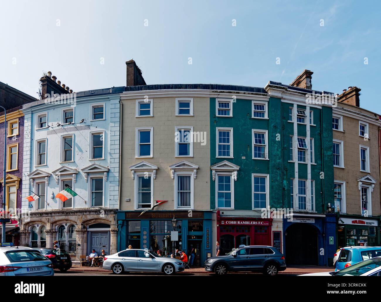 COBH, IRLAND - 15. August 2025: Eine Reihe von bunt bemalten georgianischen Gebäuden säumt den historischen Hafen von Cobh, ein beliebter Zwischenstopp für Touristen und Cru Stockfoto