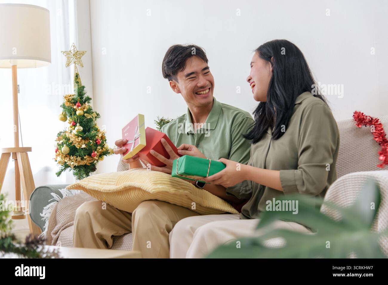 Weihnachten, glückliches Paar zeigt Liebe im Urlaub und öffnet Geschenke in der Nähe von festlichem Baum in gemütlichem Haus Stockfoto