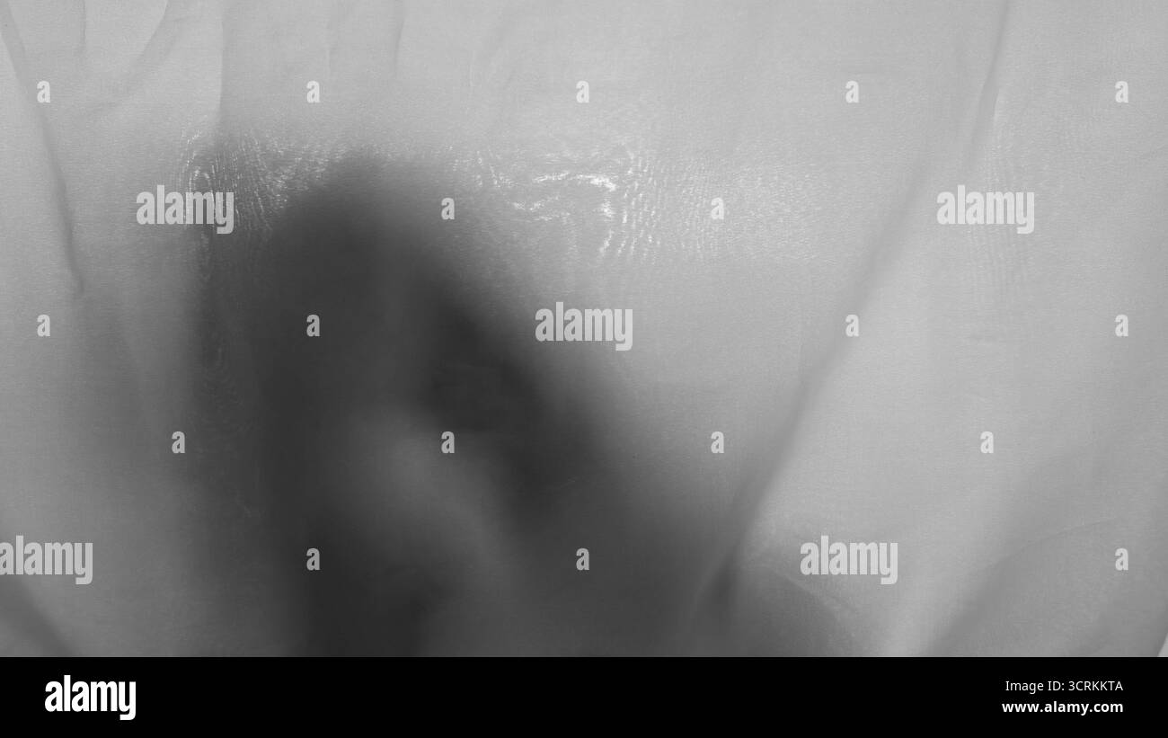 Schwarz-weißer Kopf und Hände des Menschen durch dünnes, weißes, durchscheinendes Gewebe. Der Stoff ist zerknittert und weiche Wellen erzeugen strukturierte Background-Grou Stockfoto
