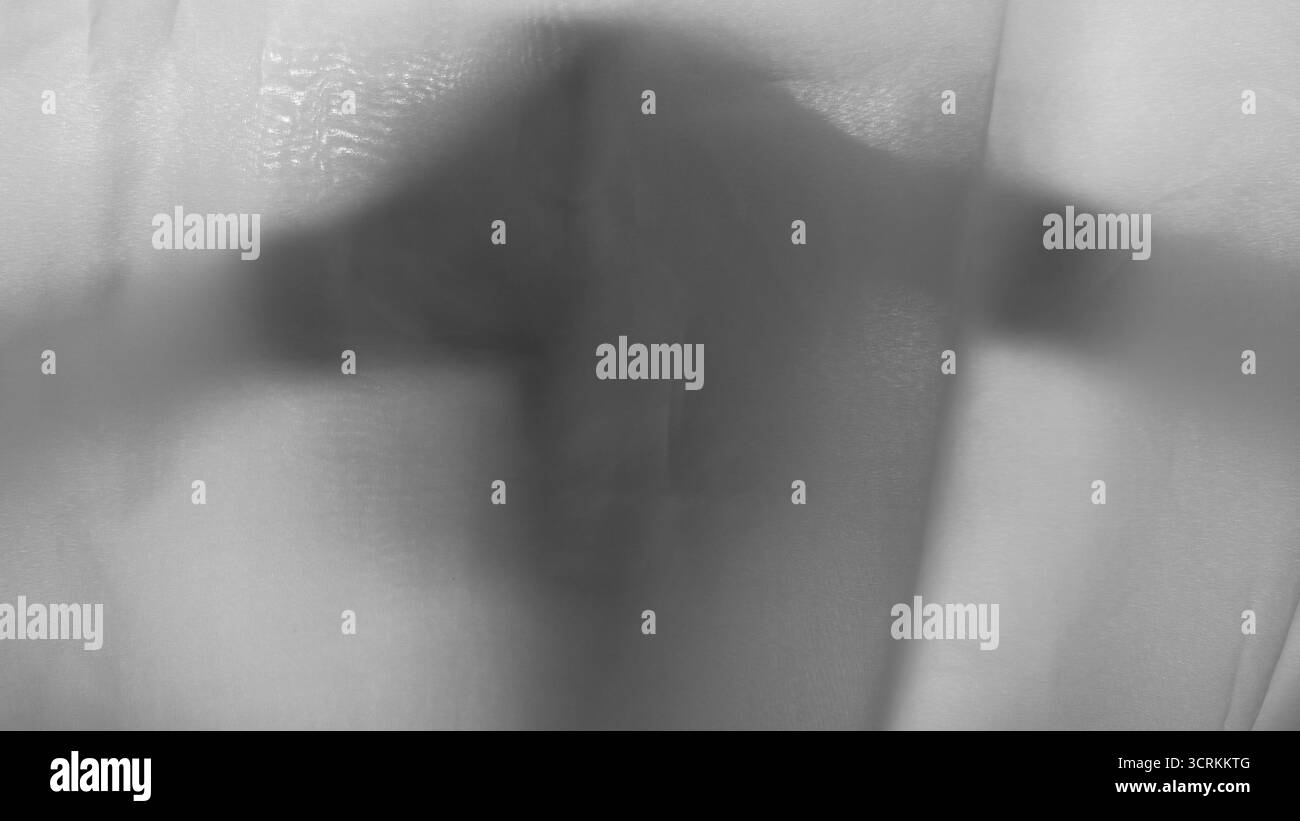 Schwarz-weiße Nahaufnahme des menschlichen Kopfes und der Hände schatten durch dünnes, weißes, durchscheinendes Gewebe. Zerknitterte Stoffe und weiche Wellen sorgen für eine strukturierte Rückseite Stockfoto